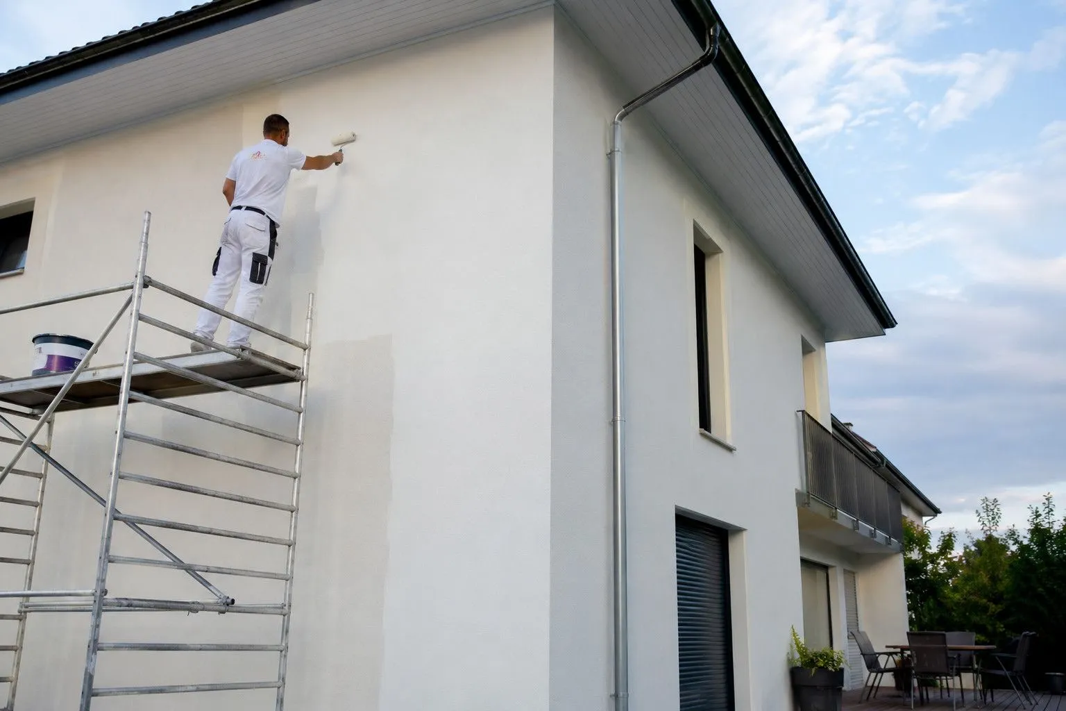 Peintre au rouleau sur échafaudage pendant le ravalement d'une façade